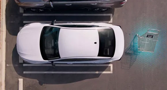 Top view of a white 2027 Nissan Altima in a parking lot with rear sensors detecting a shopping cart behind it at Holler Nissan Columbia in Columbia SC